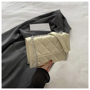 Close-up of beige quilted crossbody bag with silver chain strap and metal hardware detail
