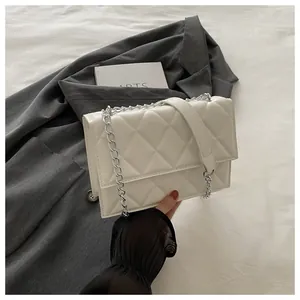 Close-up of beige quilted texture and silver chain strap on the stylish leather crossbody bag