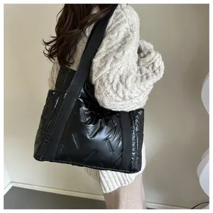 Glänzende schwarze gesteppte Puffer-Tote-Bag am Model für einen modischen Winterlook