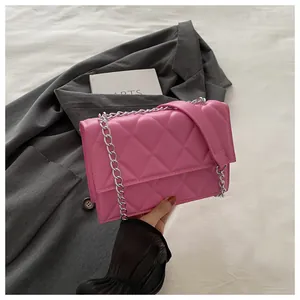 Detail of pink quilted shoulder bag with silver chain strap on grey blazer background