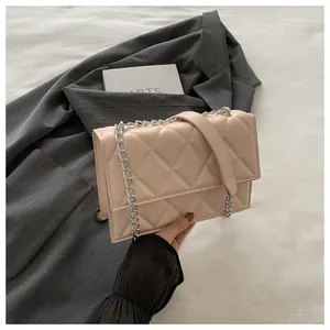 Close-up of beige quilted crossbody bag with silver chain strap and sleek faux leather finish