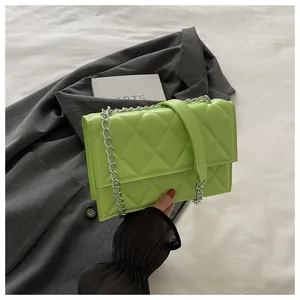 Detail shot of bright green quilted shoulder bag with silver chain strap on a blazer