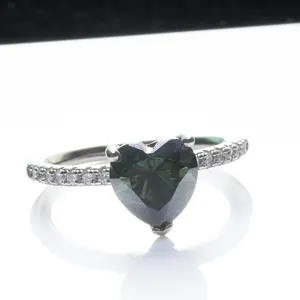 Blauwgroene hartvormige moissanite ring met zilveren band en diamanten op witte achtergrond