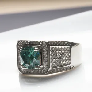 Gros plan d'une bague en argent avec pierre centrale vert émeraude et halo de diamants