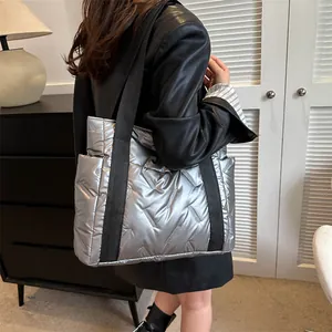 Silberne Stepp-Tragetasche mit schwarzen Riemen, präsentiert von einem Model im Innenraum