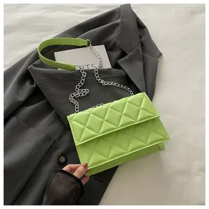 Detail of lime green quilted flap bag with silver chain strap on a grey suit jacket