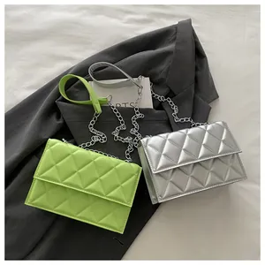 Detail of green and silver quilted crossbody bags with chain straps on gray blazer