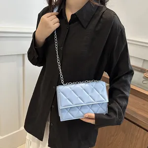 Light blue quilted crossbody bag with silver chain strap shown on a black shirt