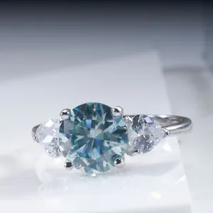 Macro de bague en argent avec pierre bleue ronde et pierres latérales poires sur monture 4 griffes