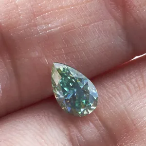 Peergeslepen blauwgroene moissanite edelsteen met briljante facetten op een vinger
