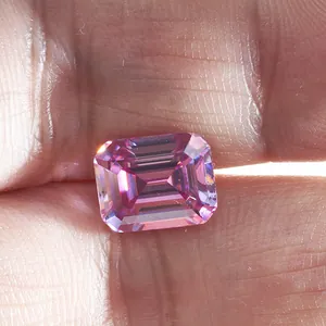 Smaragdgeslepen roze moissanite steen vastgehouden met de hand, rechthoekige facetten glans