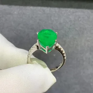 6ct pear-cut emerald silver ring with side diamonds held by hand in professional gloves