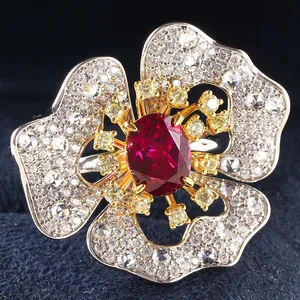 Macro detail of oval ruby ring with diamond-encrusted flower petals and gold accents