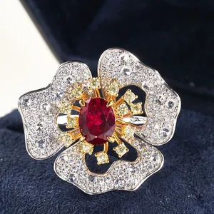 Detailed macro view of a flower-shaped ring featuring a central oval red ruby and pavé petals