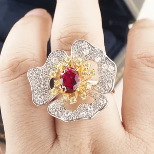 Luxurious flower ring with oval red ruby center and yellow accent stones on finger