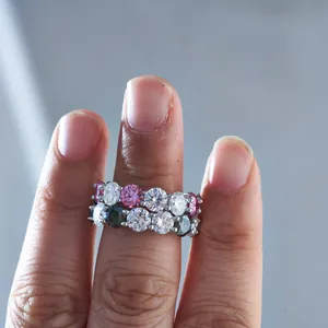 Primo piano di anelli eternity in argento S925 con moissanite rosa, bianca e verde