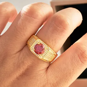 Macro detail of men's wide gold ring with large red center stone and pavé diamond band