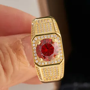 Macro shot of men's gold hip-hop ring featuring a large red gemstone and pavé stones