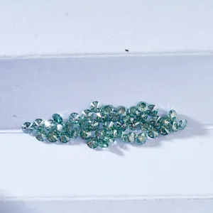 Macro-opname van diverse rond geslepen blauwgroene moissaniet edelstenen op wit papier
