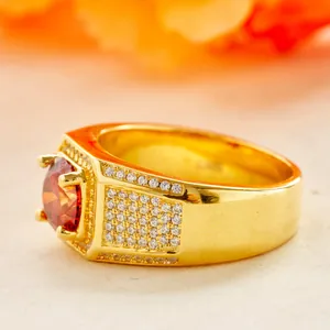 Macro view of gold-plated men's ring featuring a vibrant red gemstone and pavé-set stones