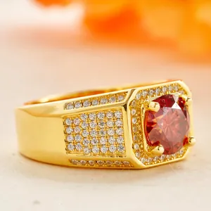 Macro detail of men's gold square ring featuring a large red round gemstone and pavé diamonds
