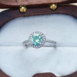 Green moissanite halo ring in silver four-prong setting displayed in luxury box