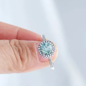 Green moissanite ring with silver four-claw setting and halo diamonds on band