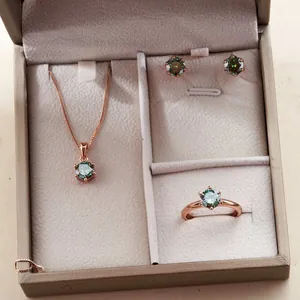 Vista detallada del conjunto de joyas en oro rosa de seis puntas con piedras azul verde