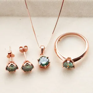 Detalle del juego de joyas en oro rosa con anillo, collar y pendientes de moissanita verde