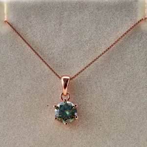 Foto macro de collar de oro rosa con gema redonda azul verdoso brillante en seis garras