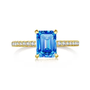 Detailed view of emerald cut blue moissanite ring with gold band and side pavé diamonds