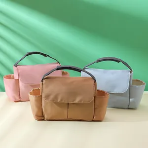 Three foldable diaper storage bags in pink, brown, and blue with side pockets and handles