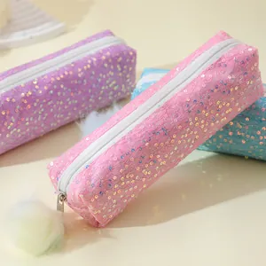 Detailed close-up of glitter sequin pencil cases in pink, purple and blue with pom poms
