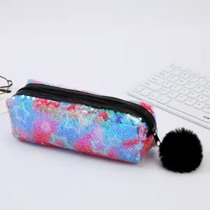 Trousse à paillettes dégradées avec motif d'étoile et pompon noir sur bureau clair
