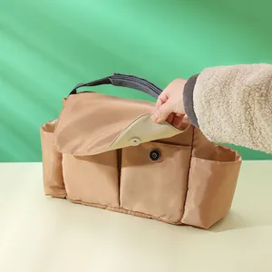 Macro detail of khaki diaper organizer bag showing magnetic snap closure and side pocket