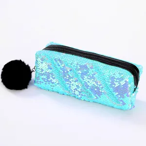Détail de la trousse à paillettes avec un grand pompon noir duveteux sur le zip