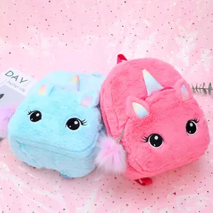 Detail of plush unicorn backpacks in blue and pink with soft texture and furry pom pom