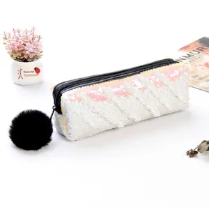 Détail de la trousse en paillettes blanches avec fermeture noire et pompon en peluche