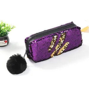 Détail de sequins réversibles violet et or sur une trousse avec pompon noir décoratif