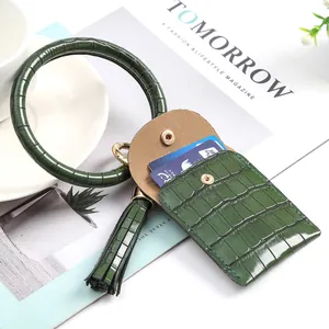Porte-cartes en cuir vert foncé à motif croco avec bracelet rond et pompon décoratif