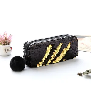 Vue détaillée de la trousse à paillettes noir et or avec un pompon en peluche douce
