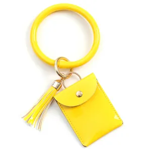Detail of bright yellow bangle keychain with mini patent leather purse and tassel charm