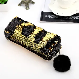 Détail de la trousse à paillettes réversibles dorées et noires avec pompon et motif LOL