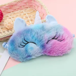 Detail of blue-purple gradient plush unicorn sleep mask with glitter horn on decorative background