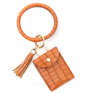 Détail du porte-clés bracelet en cuir orange gaufré crocodile avec porte-cartes et gland