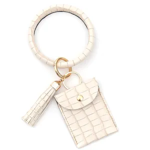 Détail du bracelet porte-clés en cuir croco blanc crème avec porte-cartes et gland
