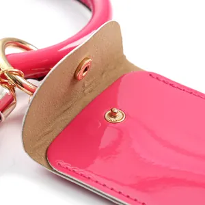 Close-up of hot pink glossy leather mini pouch with gold metal clasp and button