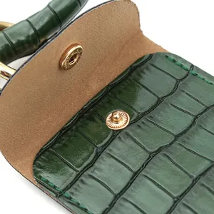 Vue détaillée d'un porte-monnaie vert foncé à motif crocodile et bouton métallique doré