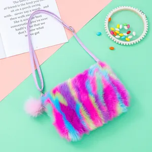 Close-up of rainbow plush crossbody bag with adjustable strap and fluffy pompom detail