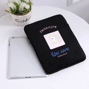 Detalle de funda de peluche negra para tableta con bordado de unicornio y cremallera